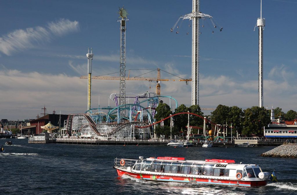 Ein Personenschiff fährt Im Wasser und im Hintergrund ist ein Pier mit Achterbahn in Lund