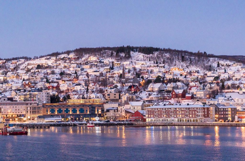 Viele eingeschneite Häuser an einem Berghang in Tromso